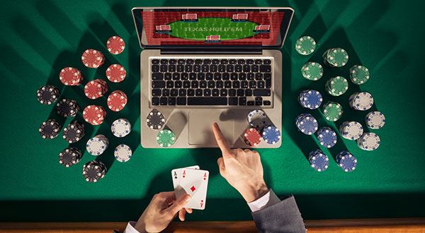 man in front of laptop which chips around and cards in hand